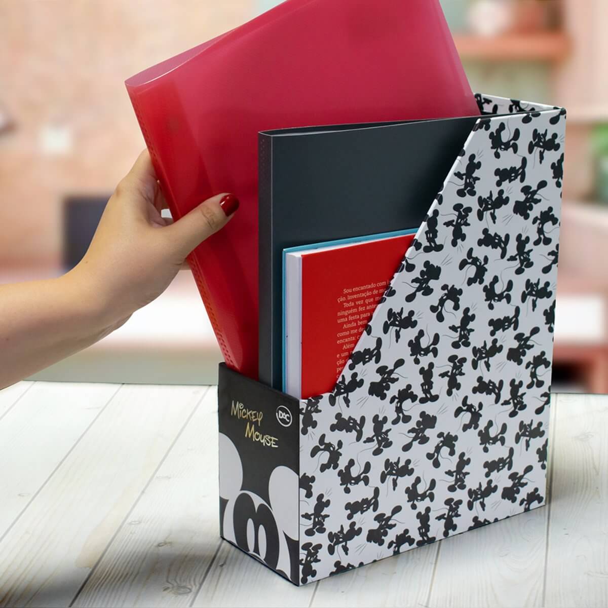 Uma pessoa colocando pastas em seu organizador de pastsa com estampa do Mickey