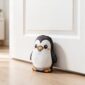 Peso de porta pinguim kawaii segurando porta branca aberta