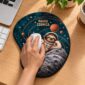 Mão utilizando o mouse pad Preguiça Pausa Cósmica em uma mesa, com apoio de pulso integrado.