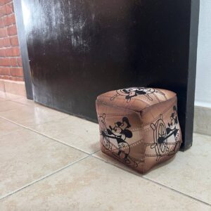 Peso de porta Steamboat Willie em formato de cubo, no chão junto à porta